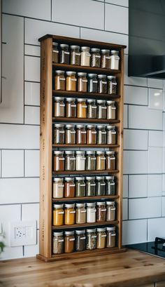 a wooden spice rack filled with lots of different types of spices on top of a counter