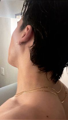 a man with no shirt is wearing a gold chain around his neck and earring