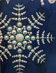 a blue and white painting with pearls on it's surface, in the shape of a snowflake