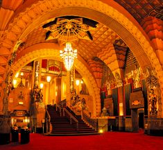 the inside of a building with red carpet and chandeliers hanging from the ceiling