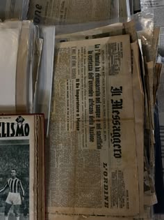several newspapers are stacked on top of each other in front of a wall with newspaper clippings
