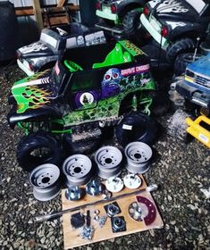 the monster truck is painted green and has wheels on it, with other parts sitting around