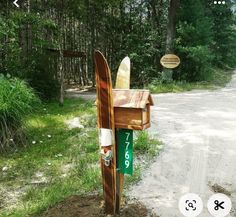 a wooden mailbox with two surfboards sticking out of it's sides on the side of a dirt road