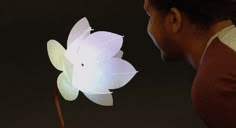 a man looking at a white flower in the dark