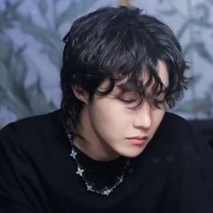 a young man sitting at a table with a pen and paper in his hand while looking down