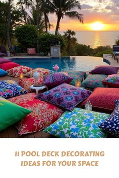 a pool deck decorated with colorful pillows and candles in front of the ocean at sunset