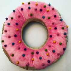 a pink donut with sprinkles on it sitting on a white surface