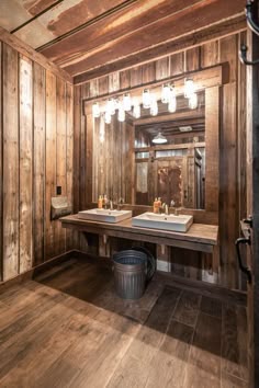 two sinks in a rustic bathroom with wood paneling on the walls and wooden floors