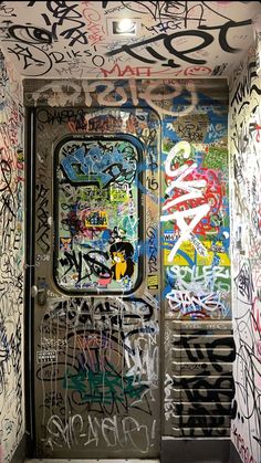 an open door with lots of graffiti on the walls and doors are covered in spray paint