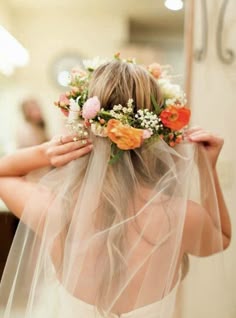 a woman wearing a veil with flowers on her head and veil over her face, in front of a mirror