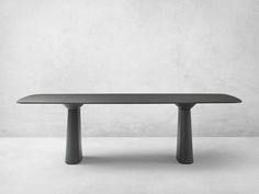 a black table sitting on top of a white floor next to a gray wall with two legs