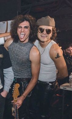 two men standing next to each other with their mouths open and one holding a guitar