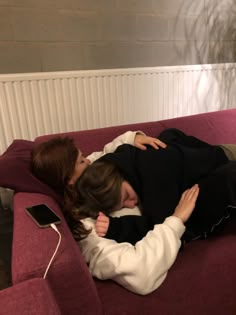 two people are laying on a couch with their heads touching each other's noses