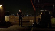 a man standing on top of a roof next to a fire hydrant at night