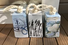 three boxes with rope tied to them sitting on a wooden floor next to a window