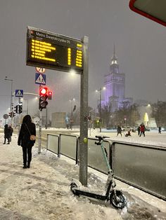a scooter parked next to a street sign on a snowy day in the city