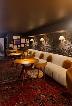 a room filled with lots of tables and chairs next to a wall covered in pictures