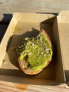 a sandwich with pesto on it sitting in a cardboard box