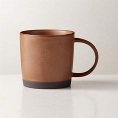 a brown coffee cup sitting on top of a white table