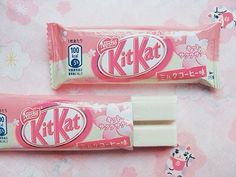 two packets of kitkat are sitting on a pink tablecloth with flowers in the background