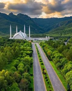 an aerial view of a large building in the middle of a green valley with mountains behind it