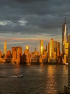 the city skyline is lit up at night, as seen from across the water with a boat in the foreground