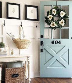 there is a blue door with white flowers on it and a wreath hanging from the wall