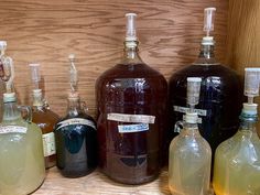 several different types of liquor bottles lined up on a shelf with labels attached to them