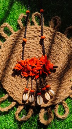 an orange and white necklace with seashells hanging from it's sides on some green grass