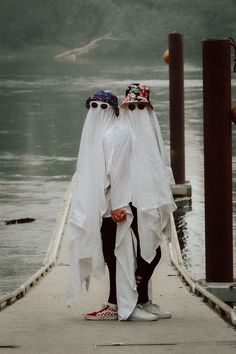 two men dressed in white standing on a dock with their heads wrapped around each other