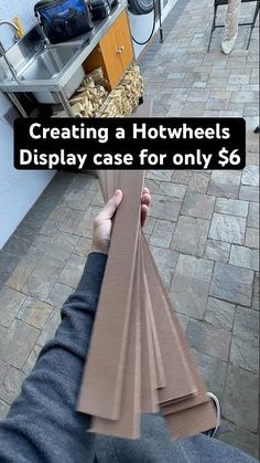 a person holding some brown paper in their hand with the words creating a hotwheels display case for only $ 6