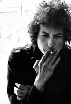 a black and white photo of a man with curly hair holding his hands to his mouth