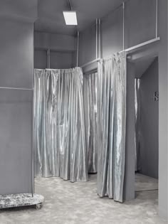 an empty room with silver curtains on the walls