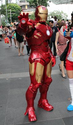 two people dressed up as iron man and girl in costumes on the street with other people