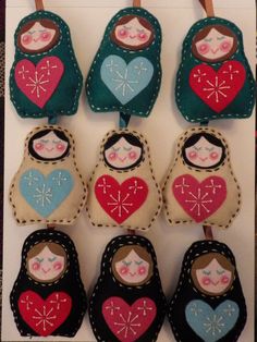 several felt dolls hanging from clothes pins with heart shaped faces and hands on top of them