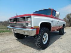 a red and white truck parked on top of a dirt road