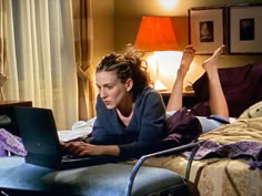 a woman laying on her bed using a laptop computer