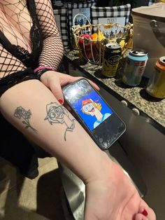 a woman sitting at a table with a cell phone in her hand and tattoos on her leg