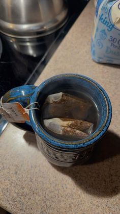 a blue mug filled with water sitting on top of a counter next to a stove
