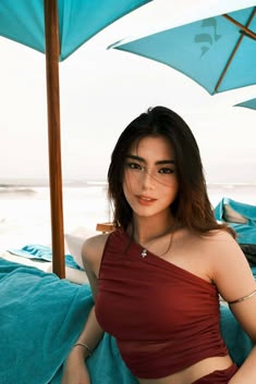 a woman sitting on top of a bed next to an open umbrella over her head