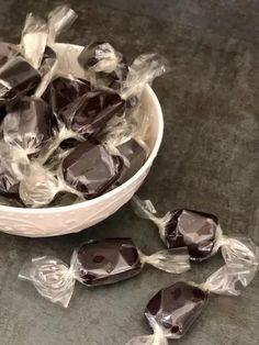 a bowl filled with chocolate candies on top of a gray counter next to plastic wrappers