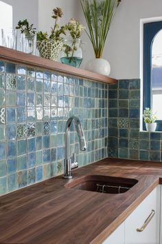 a kitchen with blue and green tiles on the backsplash, wooden countertop