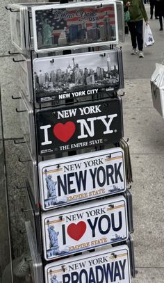 a stack of new york license plates on the sidewalk