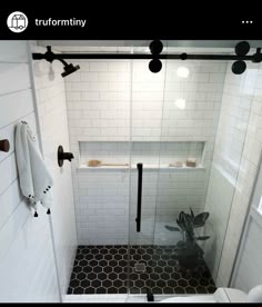 a white tiled bathroom with black and white accessories