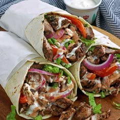 two burritos with meat and vegetables on a cutting board