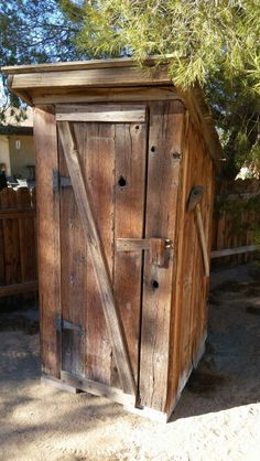 a wooden outhouse sitting in the middle of a yard
