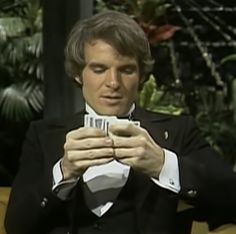 a man in a tuxedo is looking at his cell phone while sitting down