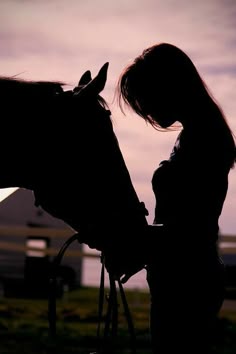 a woman standing next to a horse with its head on it's bridle