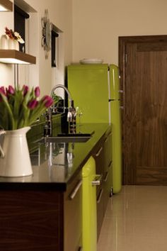 a green refrigerator freezer sitting inside of a kitchen next to a counter top with flowers on it
