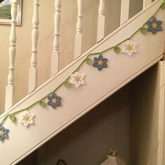 there is a white stair case with crocheted flowers on it and a green string attached to the railing